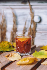 Wall Mural - A vertical shot of hot mulled pear drink with anise and cloves surrounded by autumn leaves