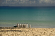 An einem Tropischen Strand stehen vor dem klaren Wasser des Ozeans aufgereihte Sauerstoff Flaschen für eine Tauchfahrt bereit und im Hintergrund sieht man eine entferne Insel
