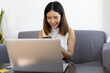 © Wasan - Asian woman working on laptop at home. Work from home and online shopping concept.