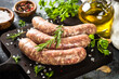 Bratwurst or sausages on cutting board with spices and herbs. Close up.