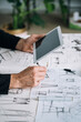 Close Up Photo of Designer Hands Drawing Blueprint and Holding Digital Tablet in his Office
