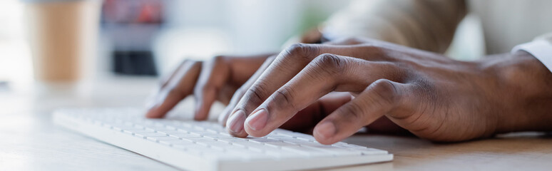 close up view of african american man typing on computer keyboard, banner.