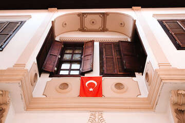 Wall Mural - The Turkish national flag hangs on the wall of the building by the window. Patriotism concept.