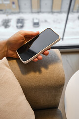 A man is holding a modern smartphone, sending a text message or using an application on his mobile phone. Business concept. Smartphone close-up. Focus on the phone screen