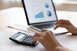 © fizkes - Woman sit at table use laptop and calculator, work on project, calculate bills, check company financial statement, pc screen with economic graphs and charts close up. Statistics, accounting concept