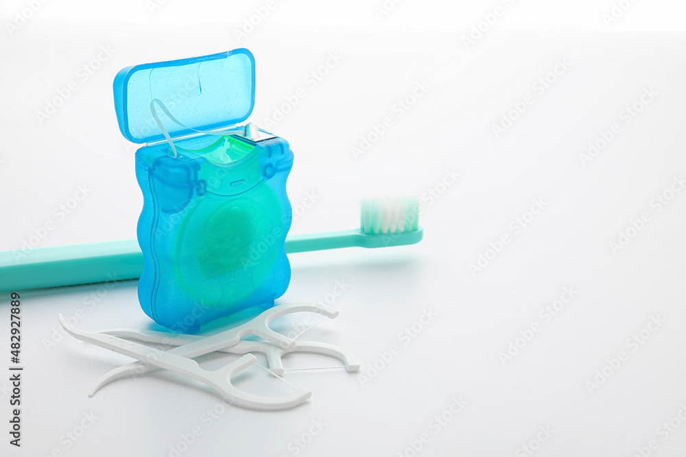 Dental floss with toothpicks and brush on white background