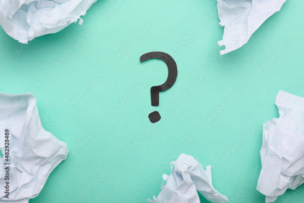 Crumpled paper and question mark on green background