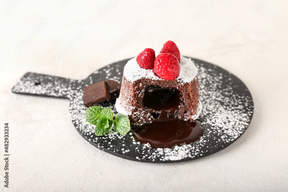 Slate board with tasty lava cake fondant and raspberry on white background