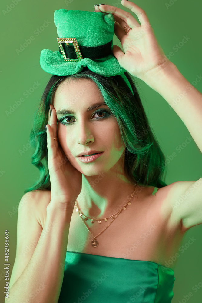 Stylish young woman dressed for St. Patrick's Day party on green background
