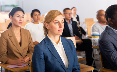 Canvas Print - Young focused woman sitting and listening to speaker at business conference