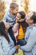 © Strelciuc - Family of four posing for family album, parents holding son and daughter in arms, kissing and hugging. Happy family spending time together.