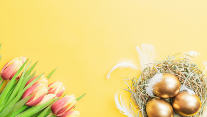 Wall Mural - Golden easter colour eggs in basket with spring tulips, white feathers on pastel yellow background in Happy Easter decoration. Spring holiday top view concept.