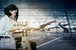 © Creativa Images - Woman using a cellphone with airplane background