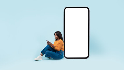 Black woman leaning on white empty smartphone screen, using cellphone