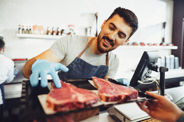 Wall Mural - Butcher's shop seller helps to choose product to woman customer