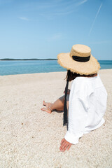 Wall Mural - young pretty stylish woman sitting at beach looking at sea