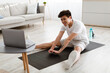 © Prostock-studio - Asian guy doing stretching exercise using laptop