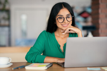 Wall Mural - Stylish indian woman independent contractor working online at cafe