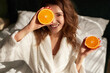 Woman with halves of orange on bed