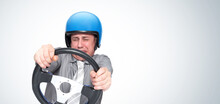 Emotional Scared Man In A Motorcycle Helmet Turning A Car Steering Wheel With His Eyes Closed. Driving School Concept 