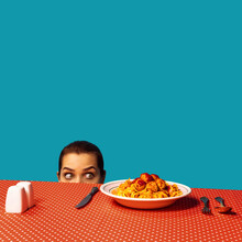Young Girl Spying On Spaghetti With Meatballs On Plaid Tablecloth Isolated On Bright Blue Background. Food Pop Art Photography. Vintage, Retro Style Interior