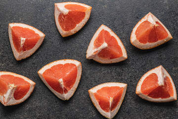 Wall Mural - Sliced citrus fruit. Chopped fresh grapefruit on black table.