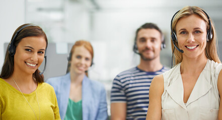 Canvas Print - We're invincible. A group of colleagues standing with headsets at the office.