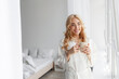 © Prostock-studio - Cheerful young cute european blonde female in bathrobe enjoy good morning, peace, quiet and drink delicious fresh coffee