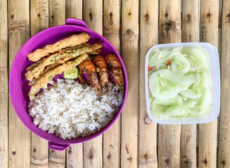 Wall Mural - meal box of rice with side dish cucumbers, fried prawns and crispy fried beans.