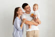 © Prostock-studio - Happy Family Of Three With Cute Infant Baby Posing Over White Background