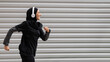 Fit muslim woman in modest sportswear and wireless headphones running outdoors