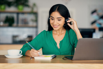 Wall Mural - Pretty indian woman attending webinar, cafe interior, copy space