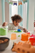 © Yakobchuk Olena - Brunette curly child playing with green kinetic sand and looking at something with interest