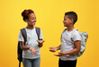 © Prostock-studio - Happy african american schoolers having conversation on yellow