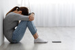 Leinwandbild Motiv Sad unhappy depressed millennial caucasian female sitting on floor with phone, covering her face