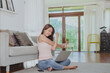 © interstid - Smiling Asian woman stretching her shoulder for relax after working from home via laptop in living room