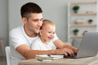 © Prostock-studio - Paternity Leave. Young Man Working On Laptop At Home With Infant Son