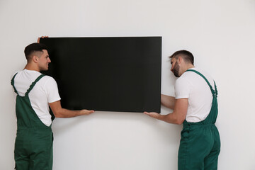 Canvas Print - Professional technicians installing modern flat screen TV on wall indoors