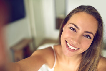 Selfie time. Shot of a young woman taking a morning selfie at home.