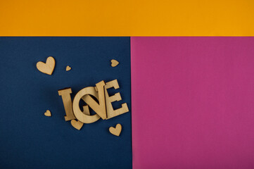 Wall Mural - Love word, small hearts on colorful paper background. Top view of Valentine's Day.