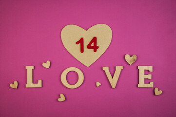 Wall Mural - The word Love with small hearts against a pink paper background closeup