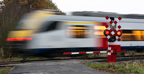 Train passes at crossing with red signal and closed barriers. 