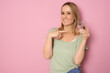 © Danko - Young smiling woman holding water glass standing isolated over pink background.