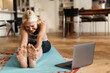 © Drobot Dean - Blonde mature woman smiling and using laptop during yoga practice