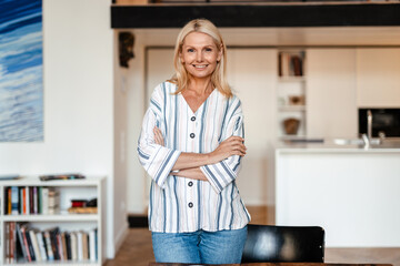 Wall Mural - Blonde mature woman smiling and looking at camera while standing