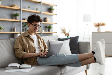 Wall Mural - Smiling asian man win glasses orking on laptop at home