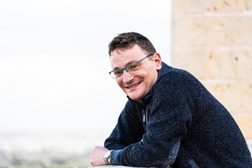 Portrait of a 42 year old white man confident and relaxed standing with a yellow and brown background