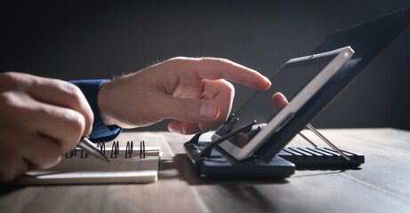 Wall Mural - Man working at tablet and writes in notepad.