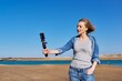 © Valerii Honcharuk - Middle aged woman on the beach talking online using smartphone.