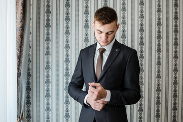 Wall Mural - A man straightens his tie, buttons his jacket, straightens his shirt